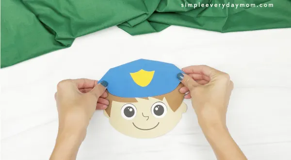 hand gluing hat to police puppet craft