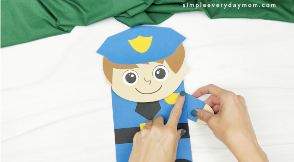 hand gluing arm to police puppet craft