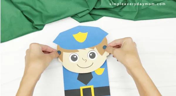 hand gluing head to police puppet craft