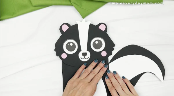 hand gluing tail to skunk paper bag craft