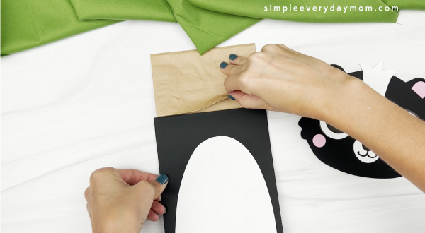 hand gluing body to skunk paper bag craft