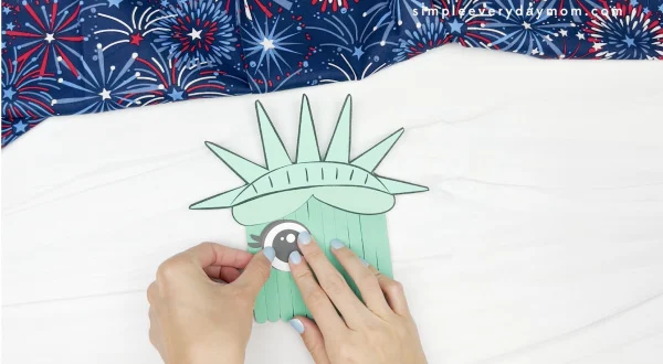 hand gluing eye to popsicle stick Statue of LIberty craft