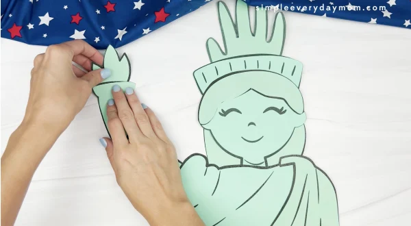 hand gluing flame to handprint Statue of Liberty craft