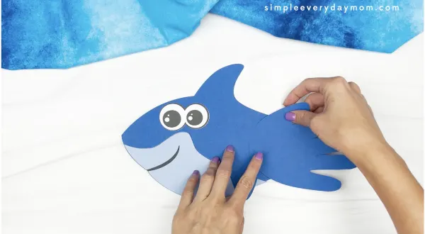 hands gluing handprint to shark handprint craft