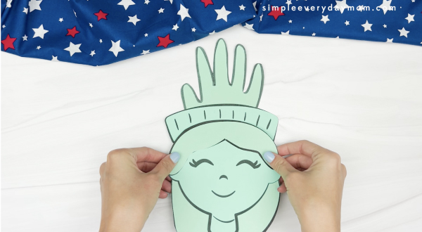 hand gluing head to crown of handprint Statue of Liberty craft