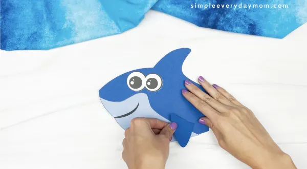 hands gluing fin to shark handprint craft