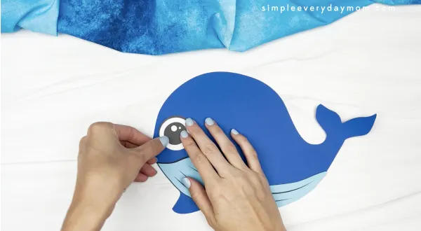 hand gluing eye to whale handprint craft