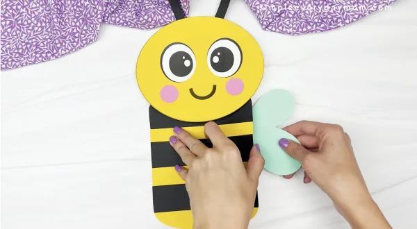 hand gluing wing to paper bag bee craft