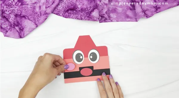 hand gluing cheeks to crayon paper bag puppet craft