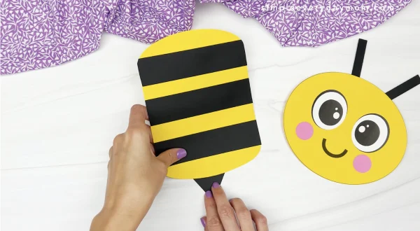 hand gluing stinger to paper bag bee craft