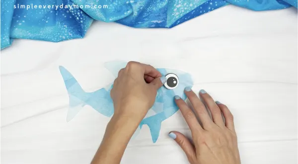 hand gluing eye onto shark suncatcher craft