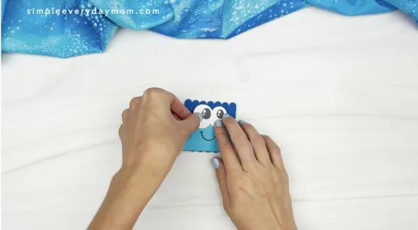 hand gluing eyes to popsicle stick shark craft