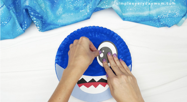 hand gluing eye to paper plate shark