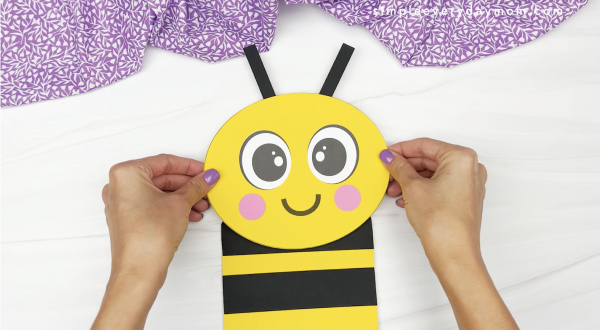 hand gluing head to paper bag bee craft