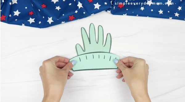 hand gluing crown to handprint Statue of Liberty craft