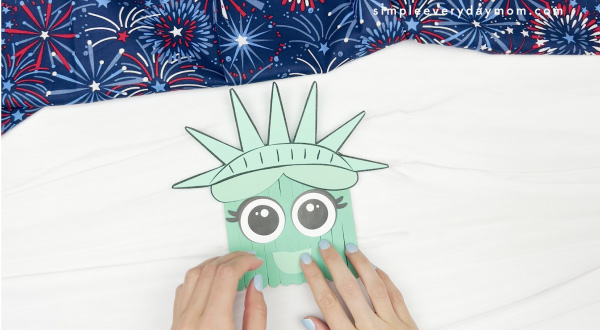 hand gluing lips to popsicle stick Statue of LIberty craft