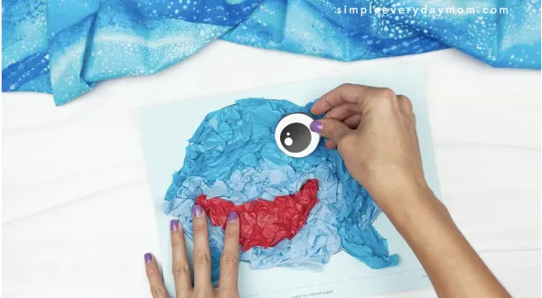 hand gluing eye to tissue paper shark craft
