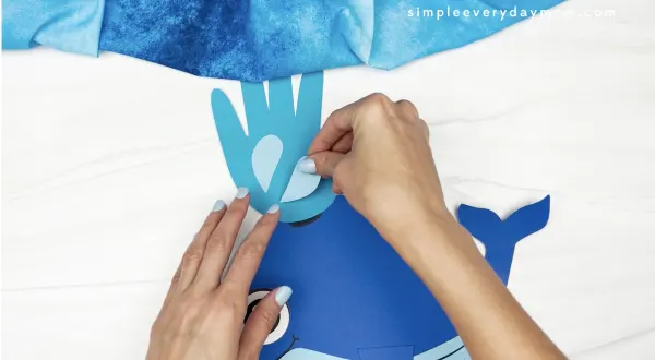 hand gluing water drops to whale handprint craft