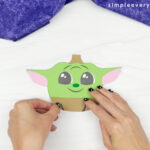 hand gluing coat to Baby Yoda pumpkin craft