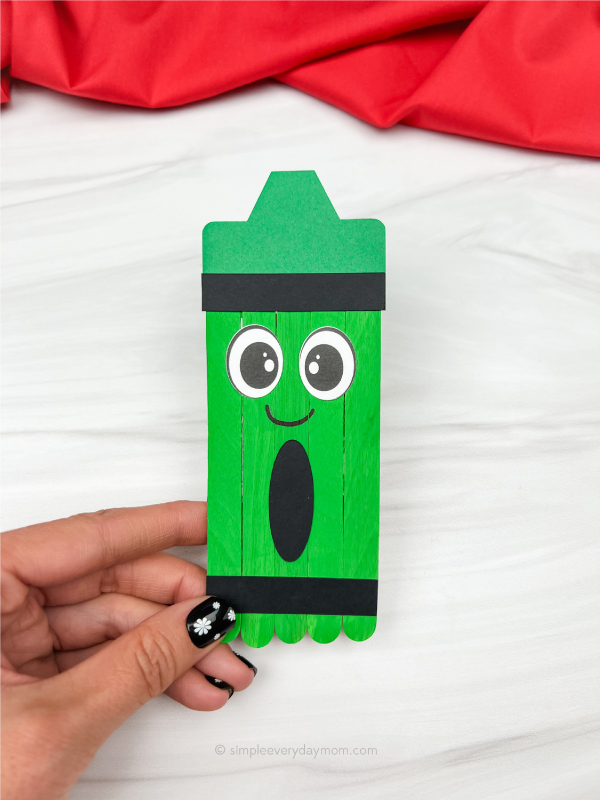 hand holding green popsicle stick crayon craft