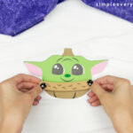 hand gluing top of coat to Baby Yoda pumpkin craft