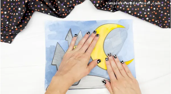 hand gluing moon to Halloween art scene