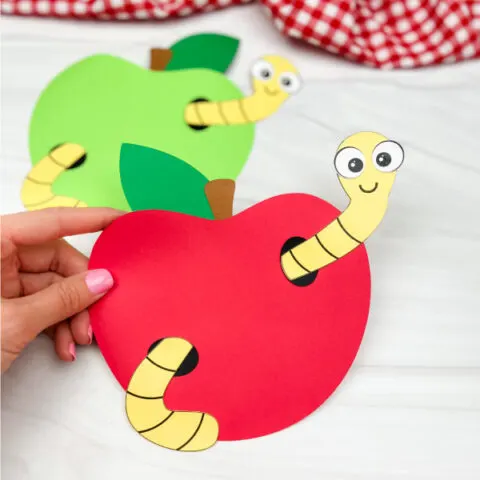 hand holding worm in apple craft with another one in the background