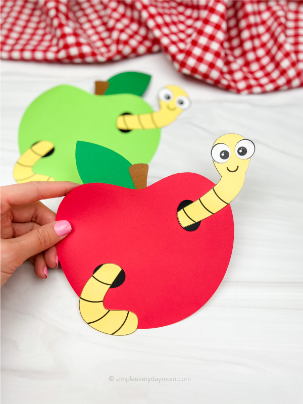 hand holding worm in apple craft with another one in the background