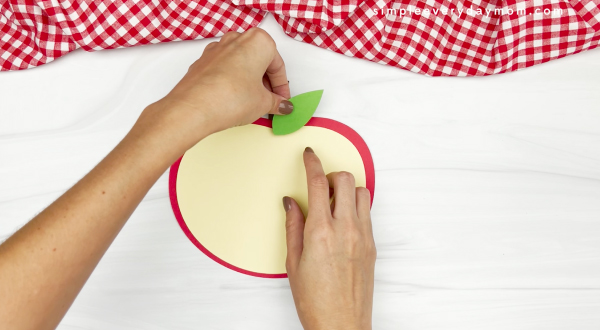 hand gluing leaf to apple name craft