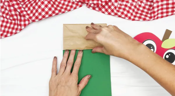 hand gluing green paper to paper bag apple craft