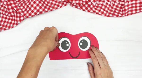 hand gluing eye to paper bag apple craft