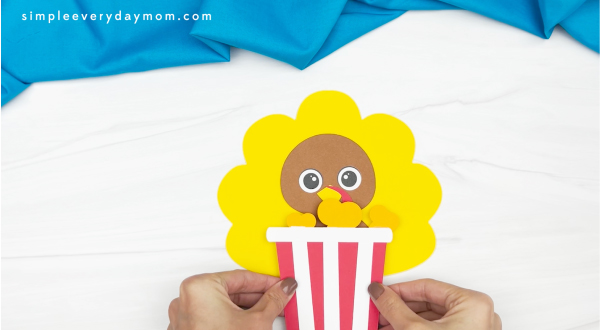 hand gluing popcorn box to popcorn turkey disguise craft