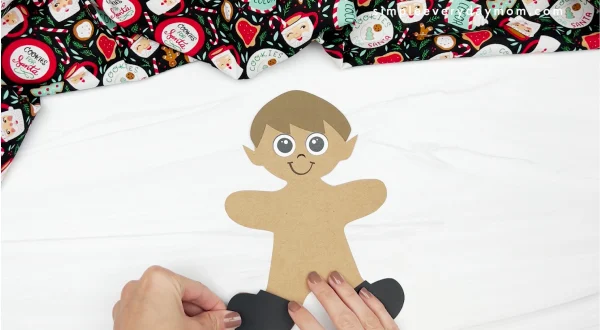 hand gluing shoes to elf gingerbread man in disguise craft