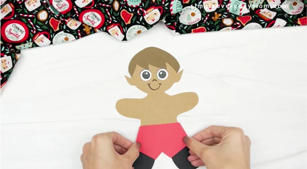 hand gluing shorts to elf gingerbread man in disguise craft