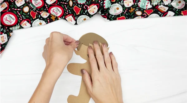 hand gluing hair to elf gingerbread man in disguise craft