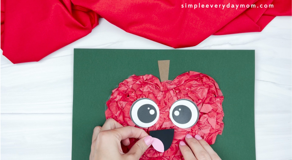 hand gluing mouth to tissue paper apple craft