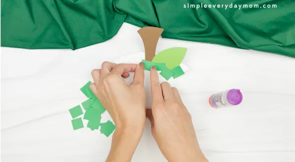 hand gluing green paper pieces to apple core craft