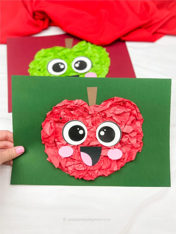 hand holding tissue paper apple craft with another one in the background