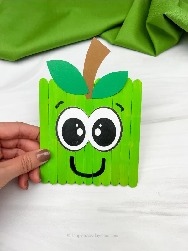 hand holding apple popsicle stick craft
