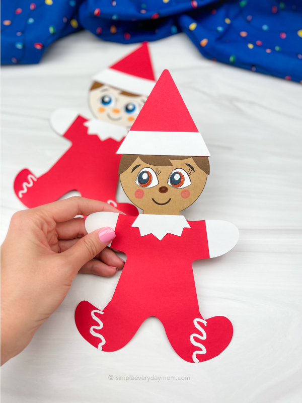 hand holding elf on the shelf gingerbread man disguise craft with another one in the background