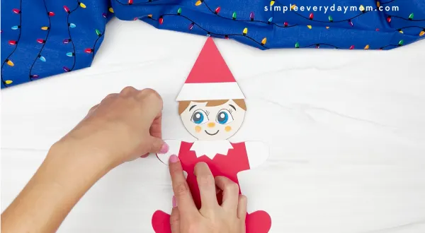 hand gluing mitten to elf on the shelf gingerbread man disguise craft