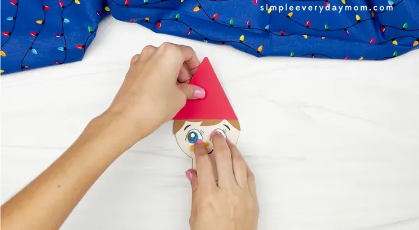hand gluing hat to elf on the shelf gingerbread man disguise craft