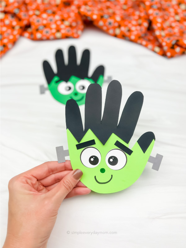 hand holding Frankenstein handprint craft with another one in the background