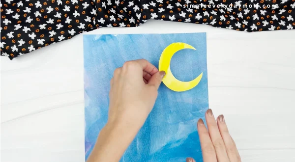 hand gluing moon to watercolor paper
