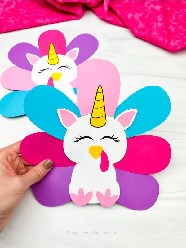 hand holding unicorn turkey disguise craft with another one in the background