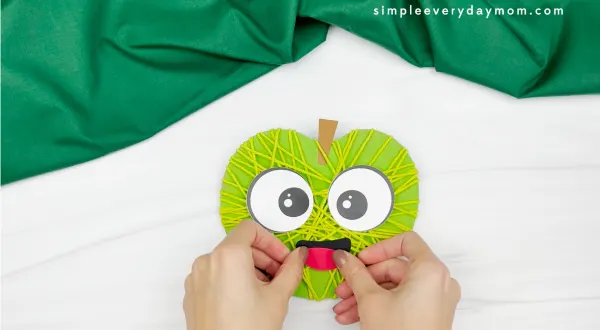 hand gluing mouth to yarn apple craft