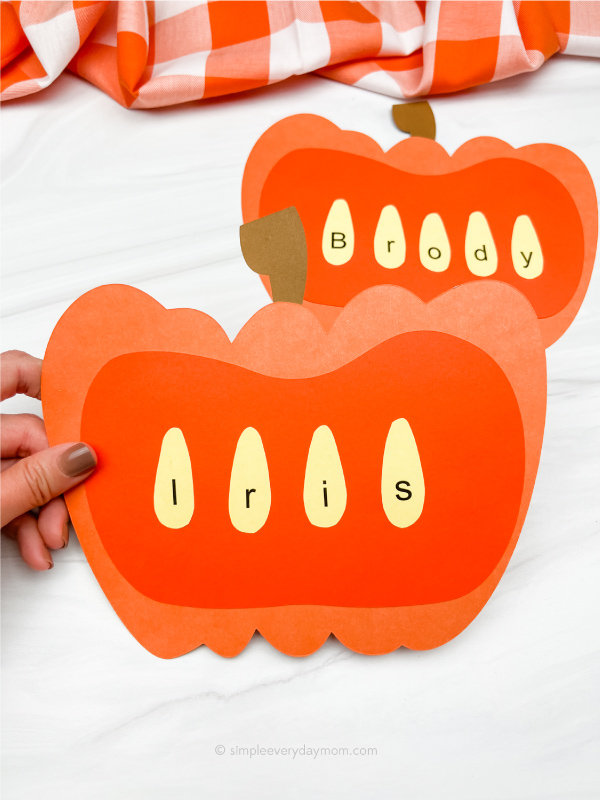 hand holding pumpkin name craft with another one in the background