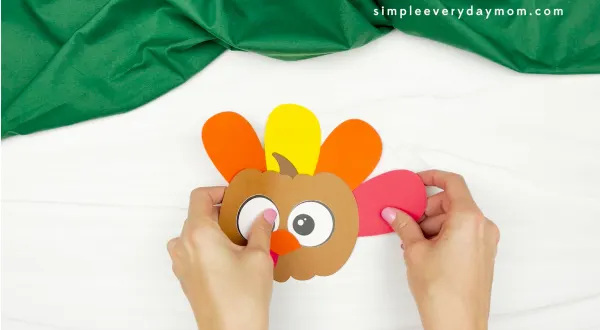 hand gluing feather to turkey pumpkin craft
