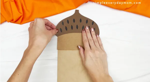 hand gluing acorn cap to paper bag acorn craft