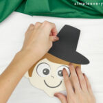 hand gluing hat to handprint pilgrim craft